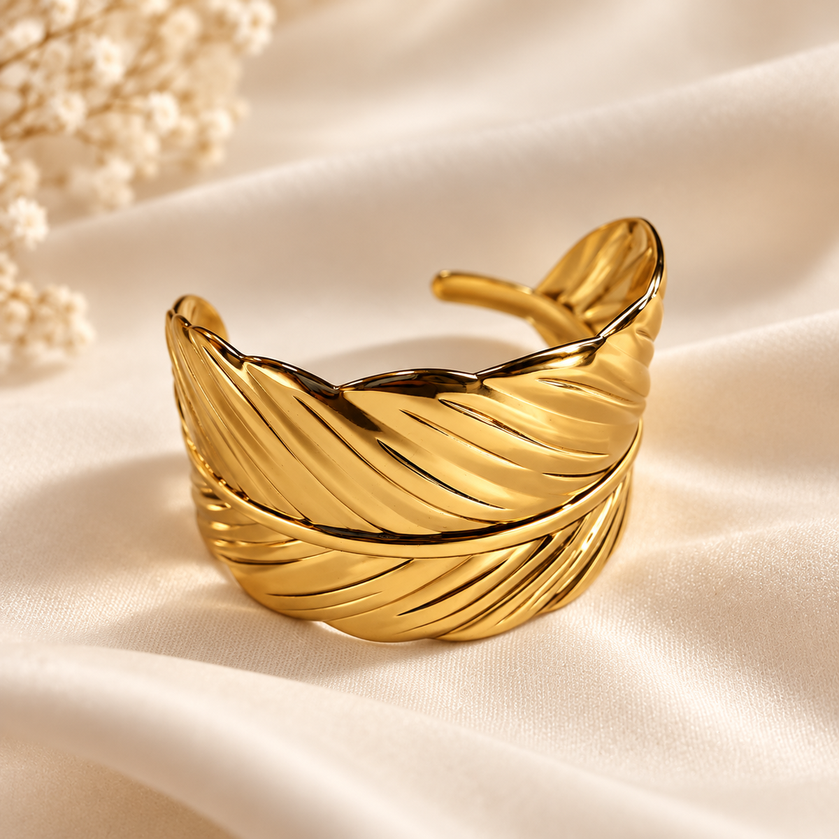 Bracelet Plume doré — sur tissu satiné.